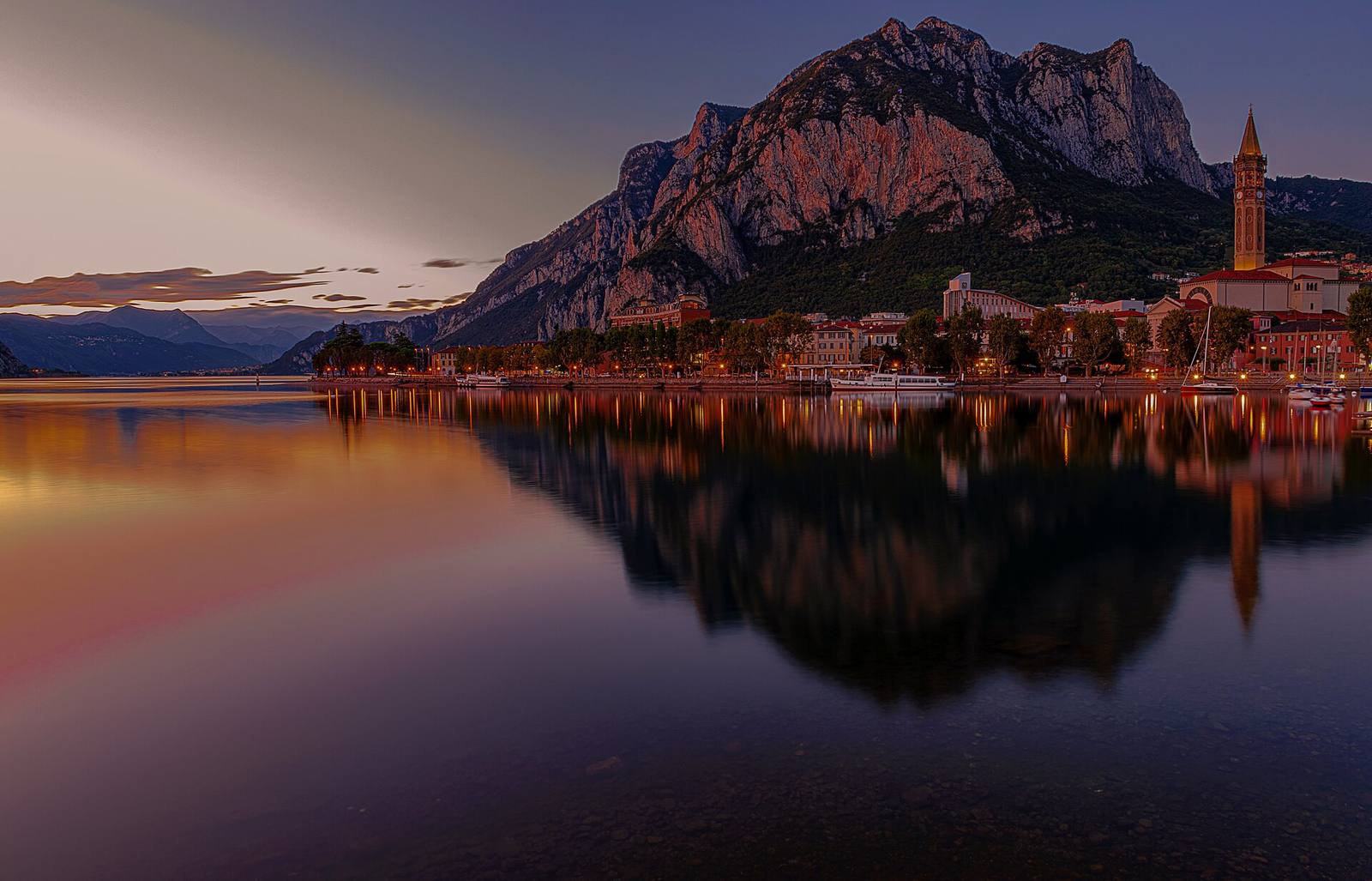 The Lecco lakefront at dusk, with the San Nicolò bell tower and Monte San Martino: the ZIS HRL network brings together the university, clinical facilities, institutions and businesses of the Lecco area.
